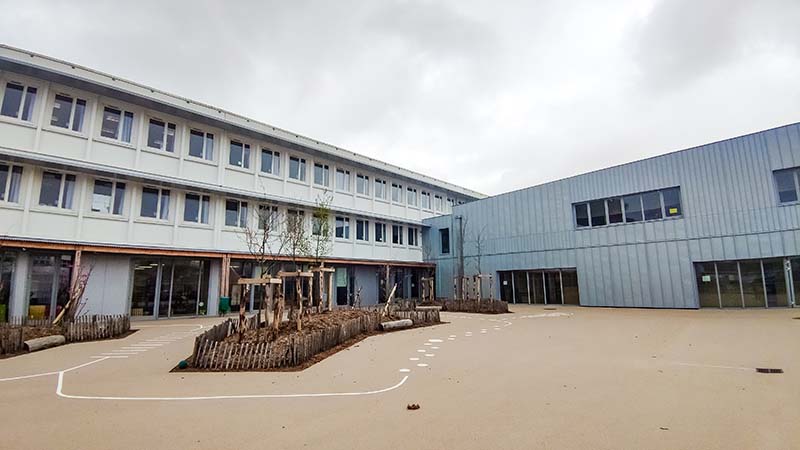 Un nouveau bâtiment (ici à droite), en bois et zinc, a été construit à la place de l’ancienne restauration. Il vient connecter l’école élémentaire (à gauche) et l’école maternelle.  © Garance Wester