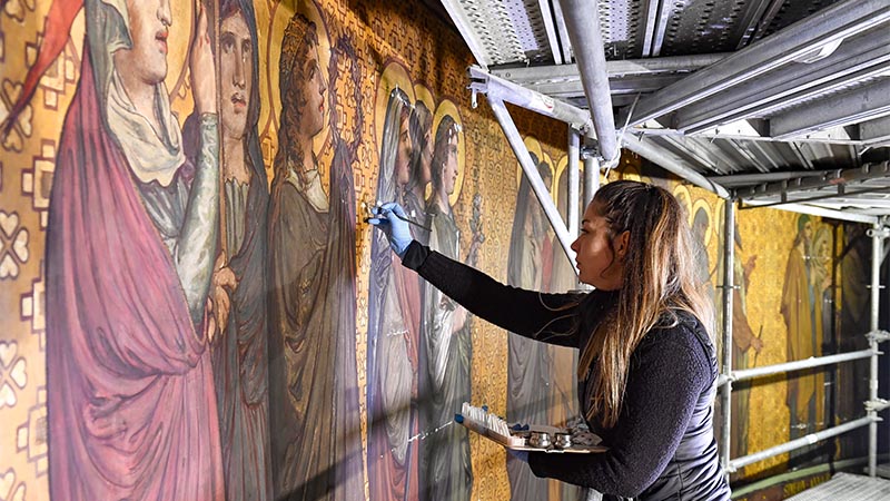 La fresque de 140 personnages couvre 155 m² de mur. Les peintres s’affairent afin de la restituer.