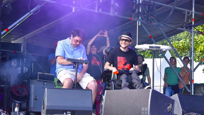 photo de deux membres du groupe jouant du pad et du clavier, assis, l'un sur un tabouret, l'autre dans un fauteuil roulant