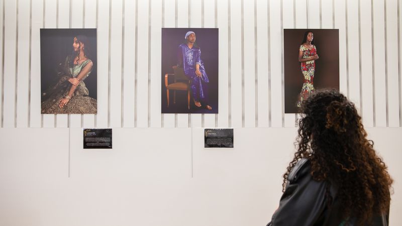 3 photographies de jeunes femmes noires et métisses sont affichées au mur sous le regard d'une femme que l'on voit de dos. 