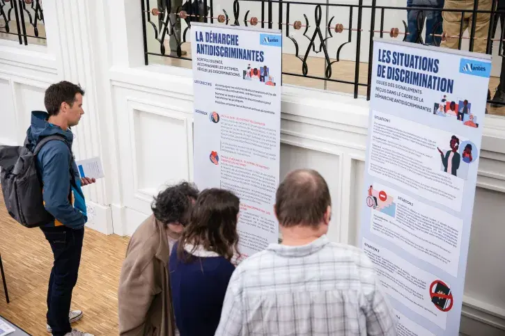 2 kakemonos de présentation de la démarche antidiscrimiNantes devant lesquels 3 personnes sont arrêtées pour lire leur contenu
